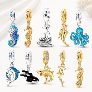Puede incluir: Una colección de diez dijes de metal en tonos plata y oro con diseños de vida marina que incluyen caballitos de mar, ballenas, delfines, un pulpo, un tiburón y una orca. Cada dije incluye una argolla marcada con S925 y pequeños cristales.
