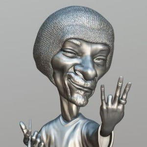 May include: A silver-colored caricature sculpture of a person with a large afro hairstyle, wearing a t-shirt and holding a joint in one hand and making a peace sign with the other. The sculpture is standing on a leaf-shaped base.