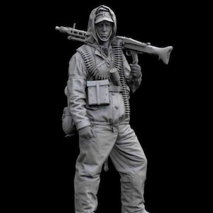 May include: A gray plastic model of a soldier wearing a winter uniform and carrying a machine gun. The soldier is standing on a gray base.
