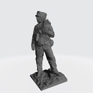 May include: A gray plastic figurine of a soldier wearing a hooded jacket and carrying a rifle and ammunition belt. The figurine is standing on a gray base.