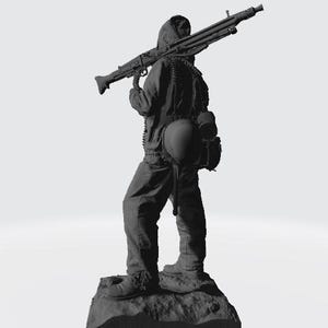 May include: A black and gray figurine of a soldier holding a machine gun. The soldier is wearing a hooded jacket and a helmet. The figurine is standing on a rocky base.