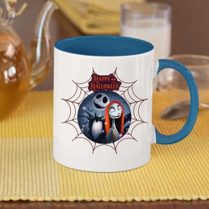 May include: White ceramic mug with a blue interior and handle. The mug features a Halloween-themed design with Jack Skellington, Sally, and the words "Happy Halloween" inside a spiderweb.