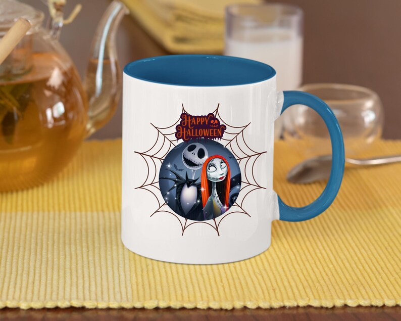 May include: White ceramic mug with a blue interior and handle. The mug features a Halloween-themed design with Jack Skellington, Sally, and the words "Happy Halloween" inside a spiderweb.