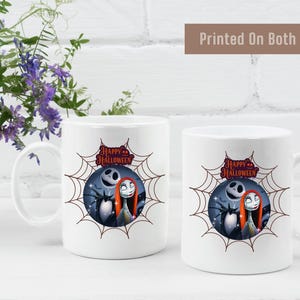 White ceramic mug featuring a colorful design with Jack Skellington and Sally inside a spiderweb frame, with pumpkins and Halloween text above.