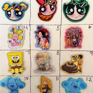 May include: A grid of twelve colorful character patches featuring various cartoon figures including Bubbles, Blossom, Buttercup, Cynthia, Selena, Homies, SpongeBob, Precious Moments, Kaa and Mowgli, Blue, and Debbie Thornberry with glitter accents.