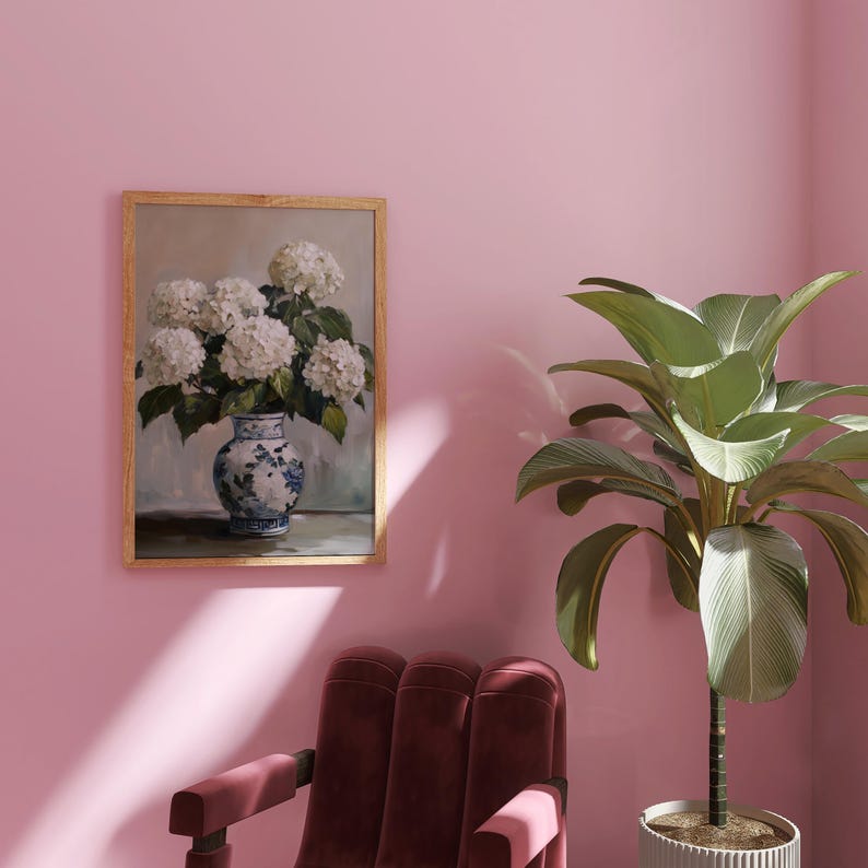 Puede incluir: Una pintura enmarcada de un ramo de hortensias blancas en un jarr&oacute;n de porcelana azul y blanco sobre un fondo gris claro.