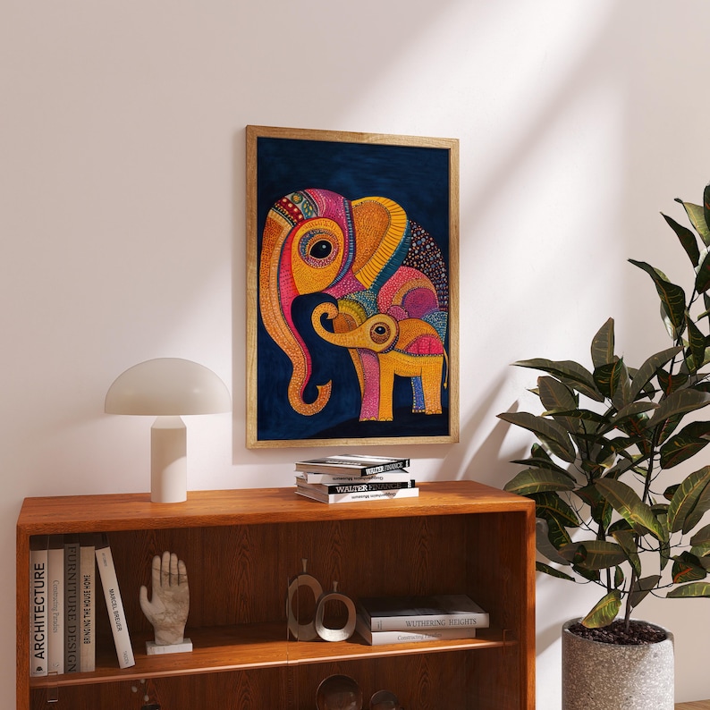 May include: A framed print of a colorful abstract painting of two elephants. The larger elephant is yellow, pink, and blue, and the smaller elephant is yellow, pink, and orange. The elephants are on a dark blue background.