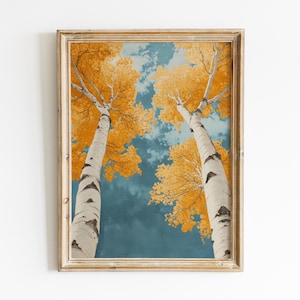 May include: A framed painting of two birch trees with yellow leaves against a blue sky. The trees are tall and slender, and their branches reach up towards the sky. The painting is in a rustic wooden frame.
