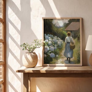 May include: A framed painting of a woman walking through a garden path lined with white hydrangeas. The woman is wearing a blue dress and carrying a basket. The painting is set against a backdrop of a green field and a small house.