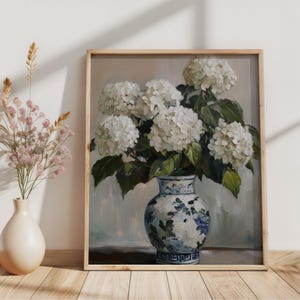 Puede incluir: Una pintura de un ramo de hortensias blancas en un jarr&oacute;n de porcelana azul y blanco. El jarr&oacute;n tiene un patr&oacute;n floral y est&aacute; sobre una mesa de madera.