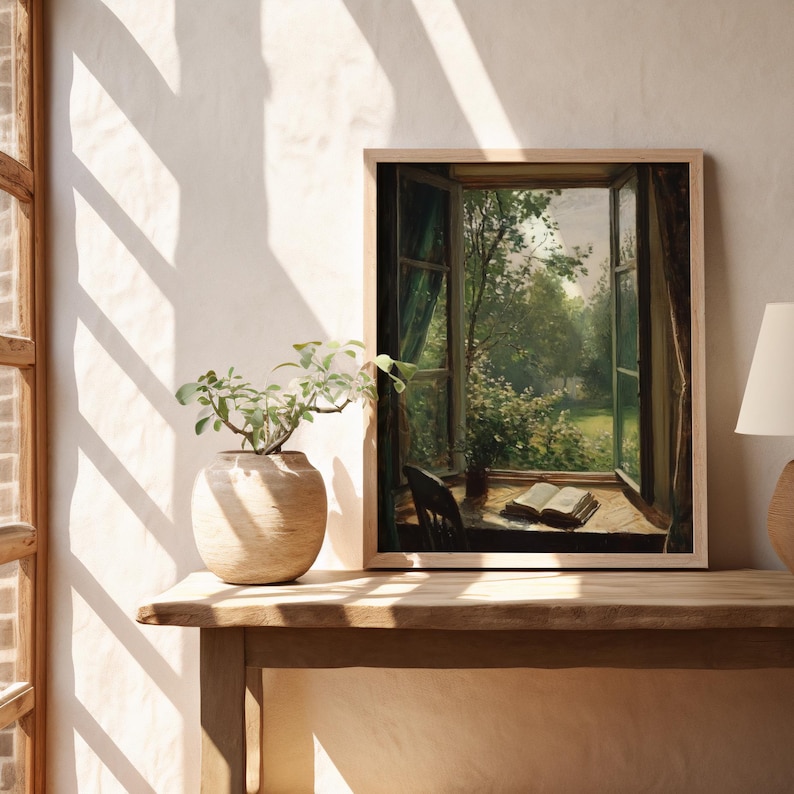 Pu&ograve; includere: Una stampa incorniciata di un dipinto che raffigura una finestra aperta con vista su un lussureggiante giardino verde. La finestra &egrave; incorniciata da tende bianche e il giardino &egrave; pieno di alberi e fiori. Un libro &egrave; aperto su un tavolo in primo piano.