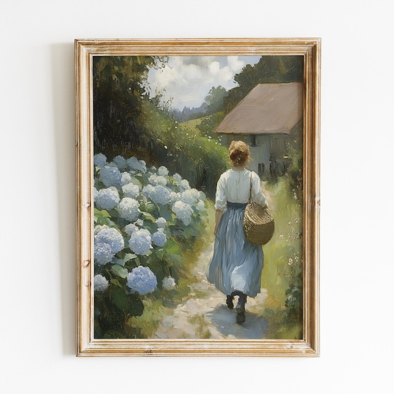 May include: A framed oil painting depicting a woman in a blue dress walking down a path lined with white hydrangeas. The woman is carrying a wicker basket and is walking towards a small cottage in the distance.