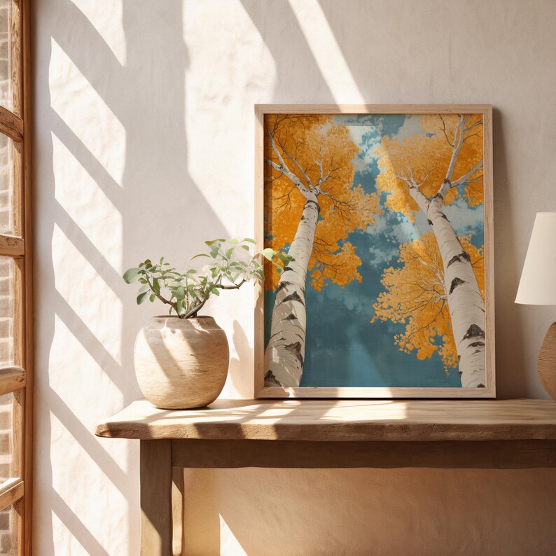 May include: A framed print of two birch trees with yellow leaves against a blue sky. The trees are reaching up towards the sky, and the leaves are a vibrant yellow.