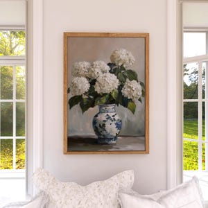 Puede incluir: Una pintura de un ramo de hortensias blancas en un jarr&oacute;n de porcelana azul y blanco. El jarr&oacute;n tiene un dise&ntilde;o floral y est&aacute; sobre una mesa.