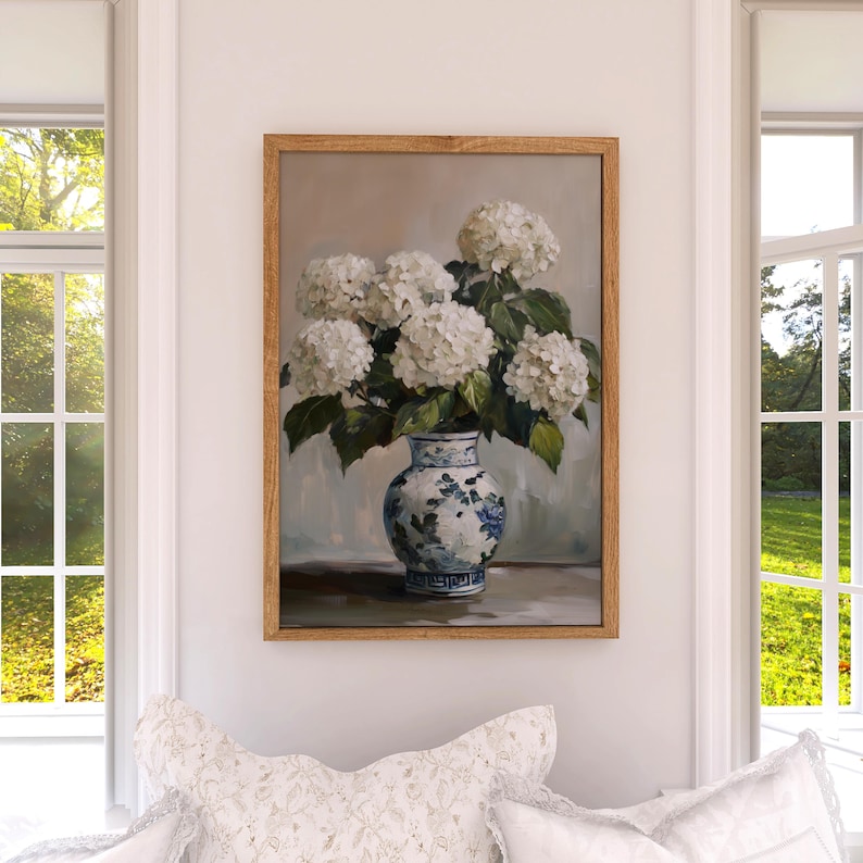 Puede incluir: Una pintura de un ramo de hortensias blancas en un jarr&oacute;n de porcelana azul y blanco. El jarr&oacute;n tiene un dise&ntilde;o floral y est&aacute; sobre una mesa.