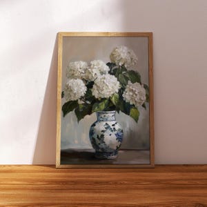 Puede incluir: Una pintura de un ramo de hortensias blancas en un jarr&oacute;n de porcelana azul y blanco. El jarr&oacute;n tiene un patr&oacute;n floral y est&aacute; sentado en una mesa.