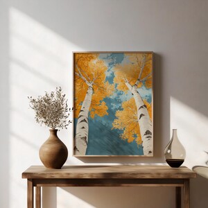 May include: A framed print of two birch trees with yellow leaves against a blue sky. The trees are tall and slender, and their branches reach up towards the sky.