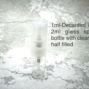 May include: A clear 2ml glass spray bottle with a clear top, half filled with 1ml of liquid. The text on the image reads: 1ml-Decanted in a 2ml glass spray bottle with clear top half filled.