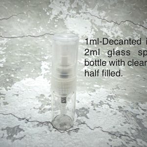 Puede incluir: Un frasco rociador de vidrio transparente con una tapa transparente, parcialmente lleno. El texto de la imagen dice: "1ml-Decantado en un frasco rociador de vidrio de 2 ml con la parte superior transparente a medio llenar."