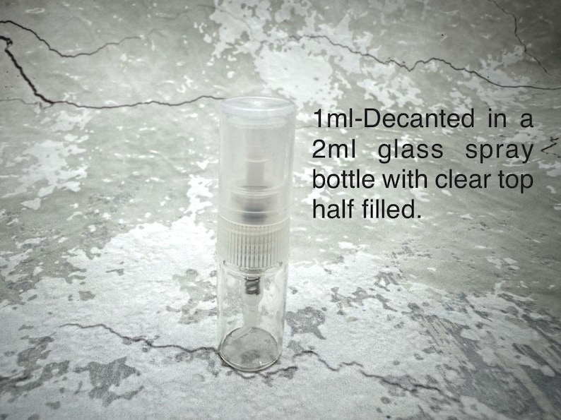 Puede incluir: Un frasco rociador de vidrio transparente con una tapa transparente, parcialmente lleno. El texto de la imagen dice: "1ml-Decantado en un frasco rociador de vidrio de 2 ml con la parte superior transparente a medio llenar."
