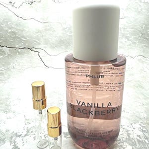 May include: A clear glass bottle of Vanilla Blackberry hair and body fragrance mist with a white cap, and two small sample bottles with gold caps. The large bottle has the text "Vanilla Blackberry" on it.