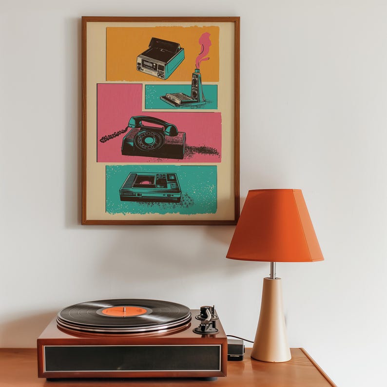 May include: A framed print with a retro design featuring a rotary phone, a vintage cassette player, and a vintage camera. The print is on a light yellow background with pink, blue, and green accents.
