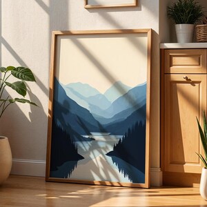 May include: A framed print of a blue and white landscape with mountains and a lake. The print is in a wooden frame and is hanging on a wall.