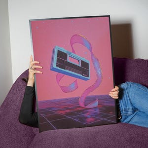 May include: A retro-style cassette player floats in a pink and blue swirling ribbon against a pink background with white stars. The player is blue and gray with a black cassette slot. The background is a grid pattern.