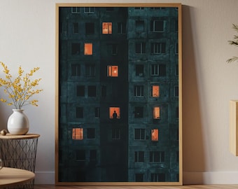 May include: Framed art print of a dark teal apartment building with several lit windows. A single figure is visible in one window. The artwork is in a wooden frame and is displayed indoors.