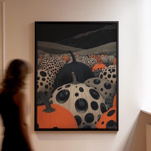 May include: Framed artwork featuring a field of pumpkins. The pumpkins vary in color, including orange, black, and cream with black polka dots. The background depicts a dark sky and rolling hills, creating a surreal landscape.