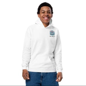 Op de afbeelding: Witte hoodie met een blauwe en roze afbeelding van een skiër op de voorkant. De afbeelding bevat de tekst "DEER VALLEY" en "SKIER" en de locatie "Deer Valley, UT".