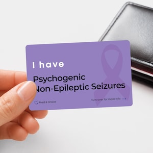 May include: A rectangular purple medical alert card featuring a dark purple awareness ribbon graphic. The text reads: I have Psychogenic Non-Epileptic Seizures, Med & Grace, and Turn over for more info with an arrow pointing to the right side.