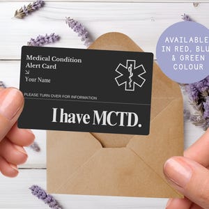 May include: A black medical alert card with white text and a medical symbol. The card reads "Medical Condition Alert Card" and "I have MCTD." The card is held in a brown envelope. Available in red, blue, and green.