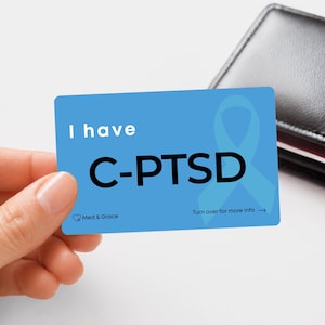 Peut inclure: Une carte de sensibilisation rectangulaire bleue avec le texte blanc I have C-PTSD en lettres noires grasses. Un ruban de sensibilisation bleu clair est imprimé sur la droite. Le logo Med & Grace figure dans le coin inférieur gauche.