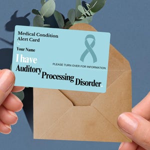 May include: A blue medical alert card with a teal ribbon and the text "Medical Condition Alert Card", "Your Name", "I have Auditory Processing Disorder", and "PLEASE TURN OVER FOR INFORMATION".