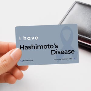 May include: A rectangular blue medical alert card featuring the text I have Hashimoto's Disease in white and black lettering, a light blue awareness ribbon graphic, the Med & Grace logo, and the instruction Turn over for more info with an arrow.