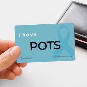 Peut inclure: Une carte d'alerte médicale rectangulaire bleu clair avec le texte blanc I have POTS, un ruban de sensibilisation bleu clair et le texte Med & Grace. La carte inclut aussi l'instruction Turn over for more info avec une flèche vers la droite.