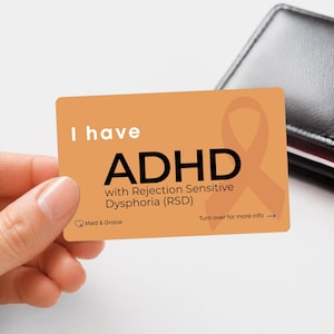 May include: A rectangular orange card featuring the white text I have and black text ADHD with Rejection Sensitive Dysphoria (RSD). The card includes a faint orange awareness ribbon, the Med & Grace logo, and the text Turn over for more info.