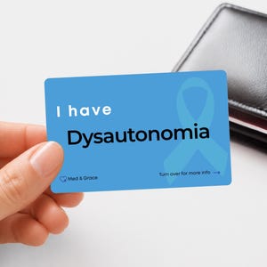 Peut inclure: Une carte d'alerte médicale rectangulaire bleue avec le texte blanc I have et le texte noir Dysautonomia. Un ruban de sensibilisation bleu clair est imprimé sur la droite. Le coin inférieur gauche affiche Med & Grace avec une icône de cœur.