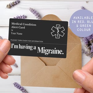 May include: A black medical alert card with white text and a medical symbol. The card reads "I'm having a Migraine." A purple circle indicates the card is available in red, blue, and green. The card is in a brown envelope.