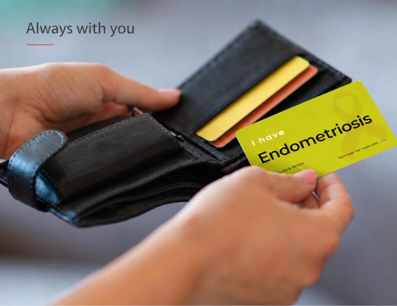 May include: A black leather wallet containing a yellow card with the text I have Endometriosis and a yellow ribbon graphic. The card also features the text Turn over for more info and the text Always with you is visible in the upper left corner.