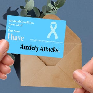 May include: A blue medical alert card with a white ribbon and the text "Medical Condition Alert Card", "Your Name", "I have Anxiety Attacks." and "PLEASE TURN OVER FOR INFORMATION".