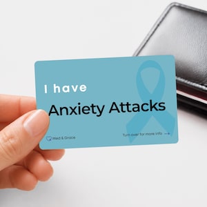 May include: A rectangular light blue card with rounded corners featuring the white text I have and the black text Anxiety Attacks. A light blue awareness ribbon is printed on the right side, with Med & Grace and Turn over for more info.