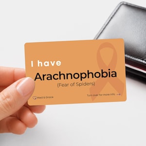 May include: A rectangular orange card featuring the text I have Arachnophobia (Fear of Spiders) in black and white lettering. The card includes a faint orange awareness ribbon graphic, the Med & Grace logo, and the text Turn over for more info.