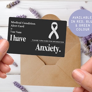 May include: A black medical alert card with the text "I have Anxiety" and a white ribbon symbol. The card is inside a brown envelope, with a purple circle that says "Available in Red, Blue & Green Colour".