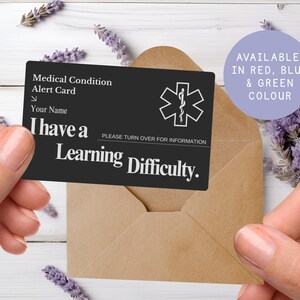 May include: A black medical alert card with white text, held in front of a brown envelope. The card reads "Medical Condition Alert Card" and "I have a Learning Difficulty." A purple circle states "Available in Red, Blue & Green Colour."