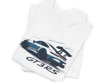 May include: White t-shirts with a graphic of a sports car in blue and white. The car has the text "GT3RS" on the side and below the car. The shirts are folded and stacked on top of each other.