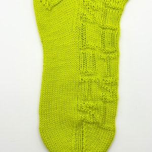 May include: A single, lime green knitted sock. The sock features a textured pattern on the side and heel. The knitted fabric is a solid, vibrant green color. The sock is displayed against a white background.