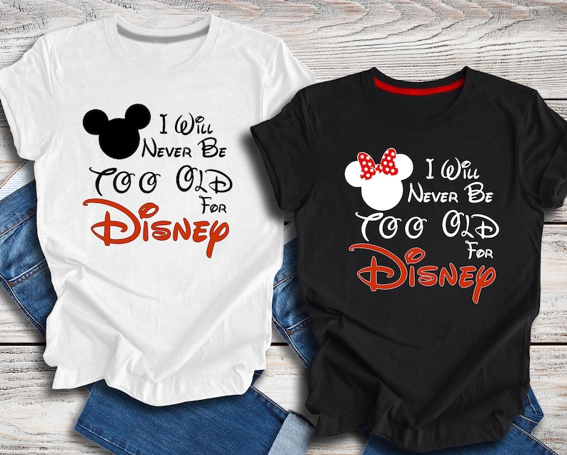 Puede incluir: Dos camisetas con un Mickey Mouse blanco y negro y un Minnie Mouse rojo y blanco. El texto en las camisetas dice "I Will Never Be Too Old For Disney".