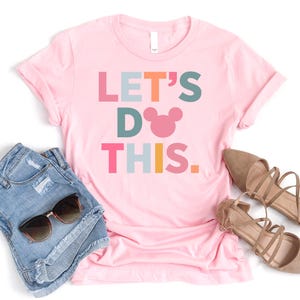 Peut inclure: T-shirt rose avec le texte "LET'S DO THIS." en lettres color&eacute;es et une t&ecirc;te de Mickey Mouse rose.